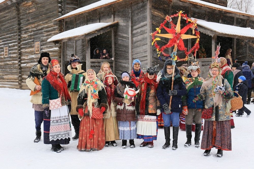 Люди в нарядах на фоне деревянного дома