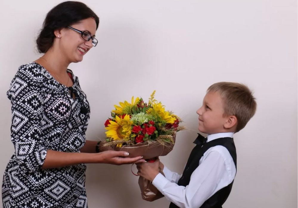 Школьник с букетом возле учителя